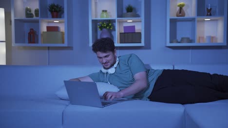 hombre riendo usando una computadora portátil por la noche.