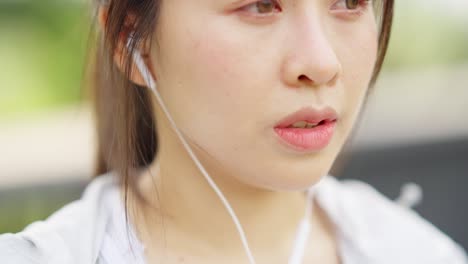 4k 아시아 여성이 아침에 공원에서 조하는 동안 음악을 듣고 있습니다.