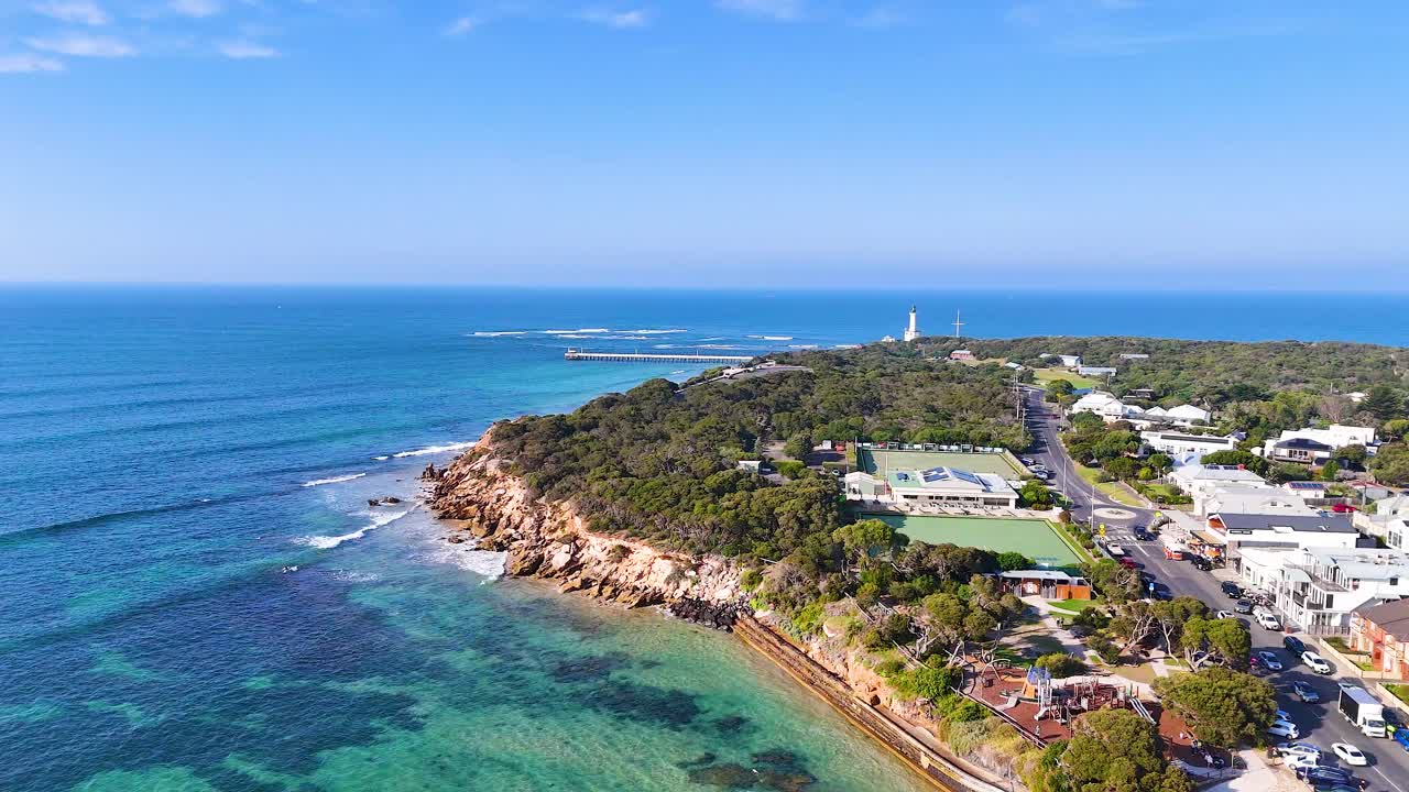 Aerial footage captures Point Lonsdale's scenic coastline, lush greenery, and iconic lighthouse under clear blue skies
