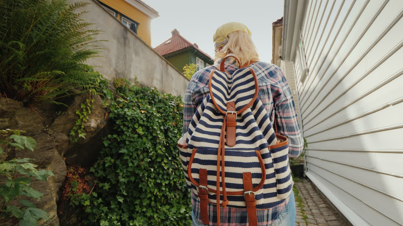 지도를 들고 노르웨이 베르겐의 좁은 거리를 걷고 있는 관광객