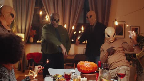 masked friends dancing at halloween home party