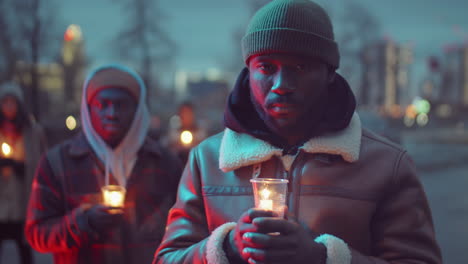 african american man holding candlelight vigil and looking at camera