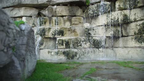 baja muñeca fuera de la toma de una cascada con una pared de piedra decorativa en un jardín