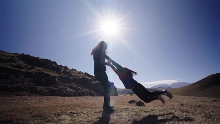 Madre che fa dondolare la figlia nella Quebrada del Portugués, Tucumán, Argentina, paesaggio montano andino.