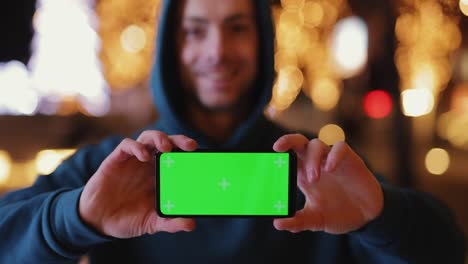 man shows empty green screen at night