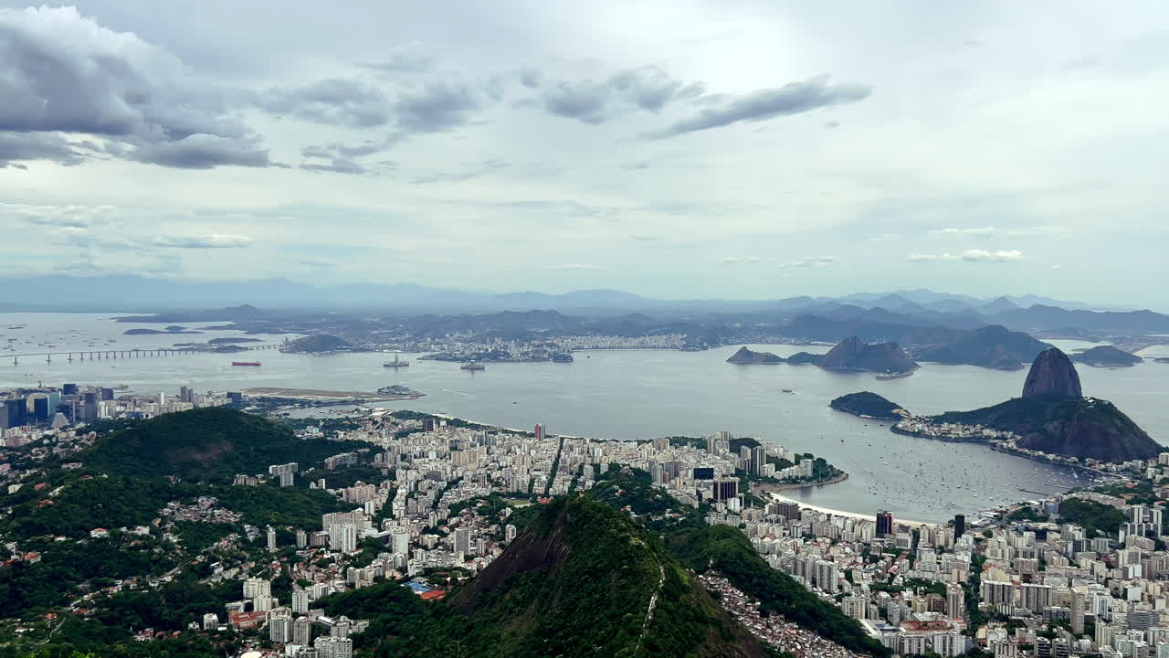 Cristo Redentor com vista para a costa da Baía de Guanabara. Vista detalhada do parque Aterro do Flamengo e das margens curvas da Praia de Botafogo, aninhada sob o icônico horizonte do Rio de Janeiro