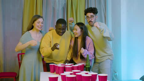 felices jóvenes amigos multiétnicos jugando al pong de cerveza en casa