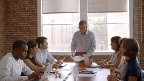 mature businessman standing to address boardroom meeting