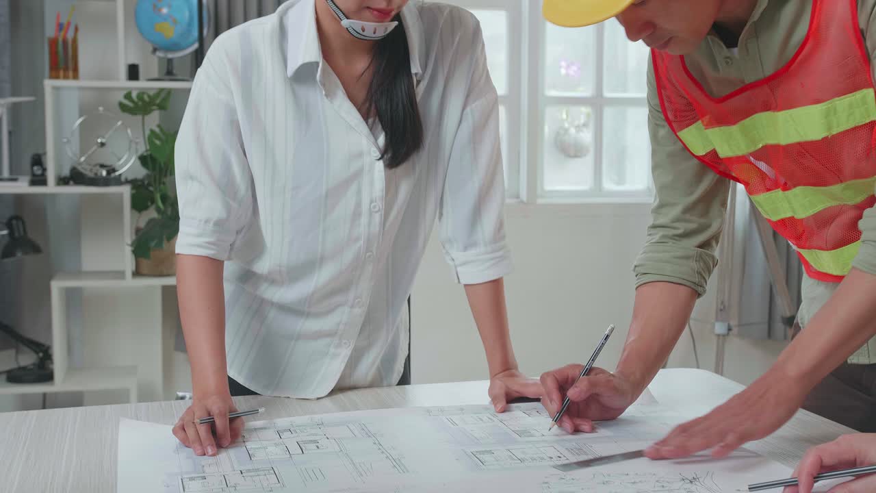 Asian Engineers With Helmets Drawing Building Construction For A Man At The Office