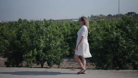 woman in a white dress walking through an orange grove