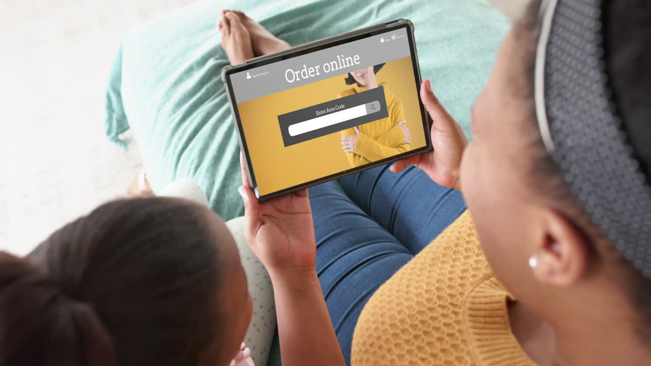 African american mother and daughter using tablet, online shopping for fashions, slow motion