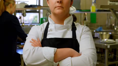 chef femenino de pie con los brazos cruzados en la cocina 4k