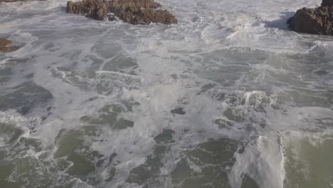 rápido, aéreo bajo sobre espumoso, rompiente en la costa del océano de aguas bravas, áfrica