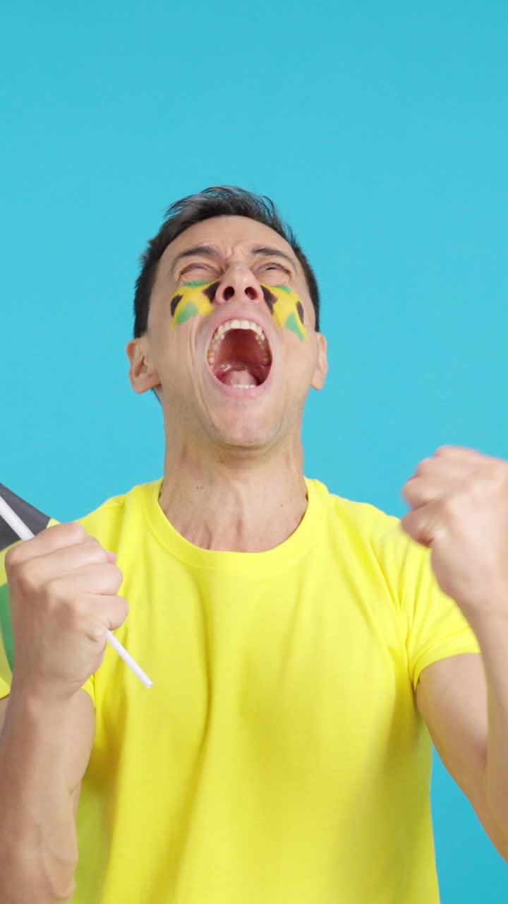 Man cheering for Jamaica screaming and waving a national flag