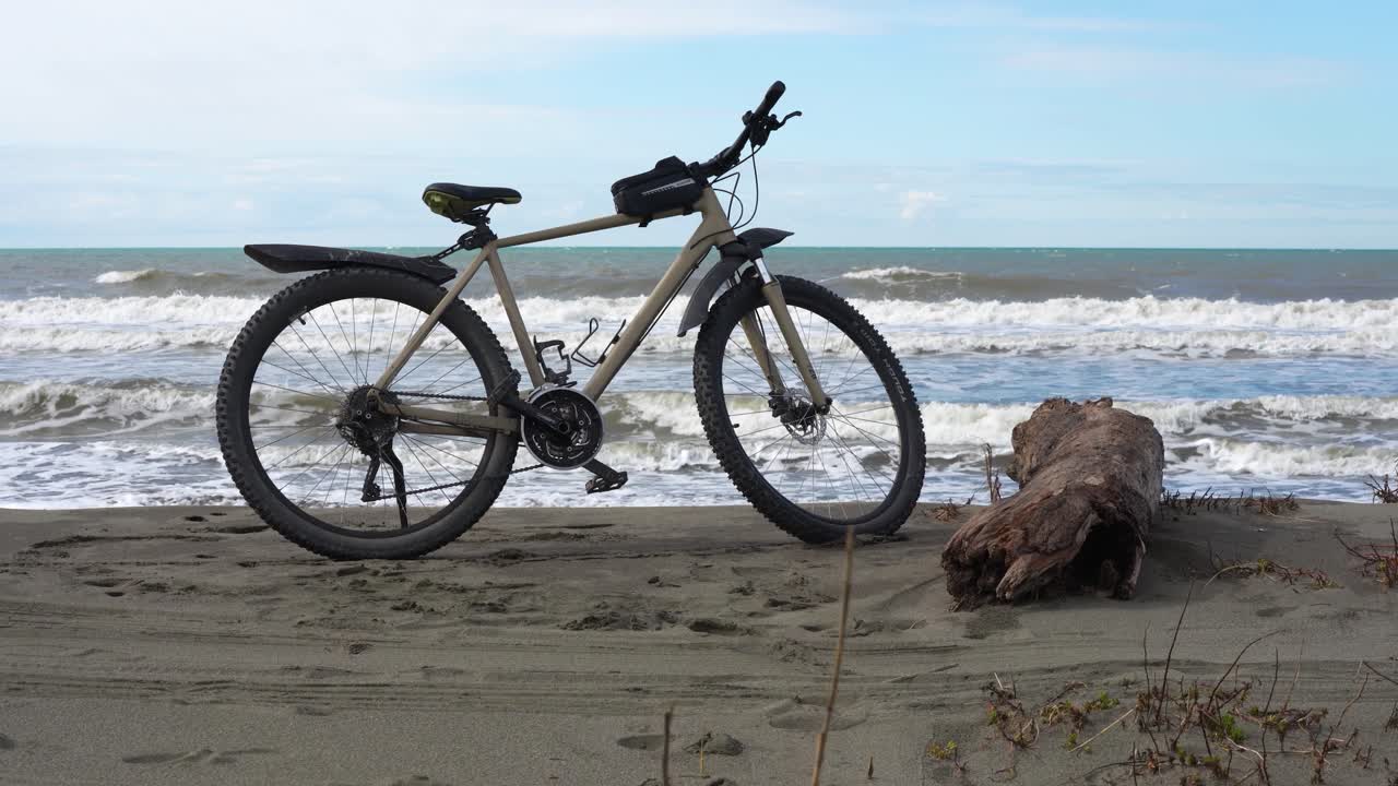 Ciclismo em uma praia arenosa remota perto das ondas do mar, realçando a paixão por esportes ao ar livre e uma vida saudável.
