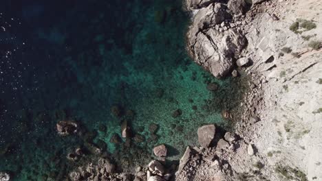 Top-down-birds-eye-view-drone-shot-rocks-and-cliff-with-ocean-water