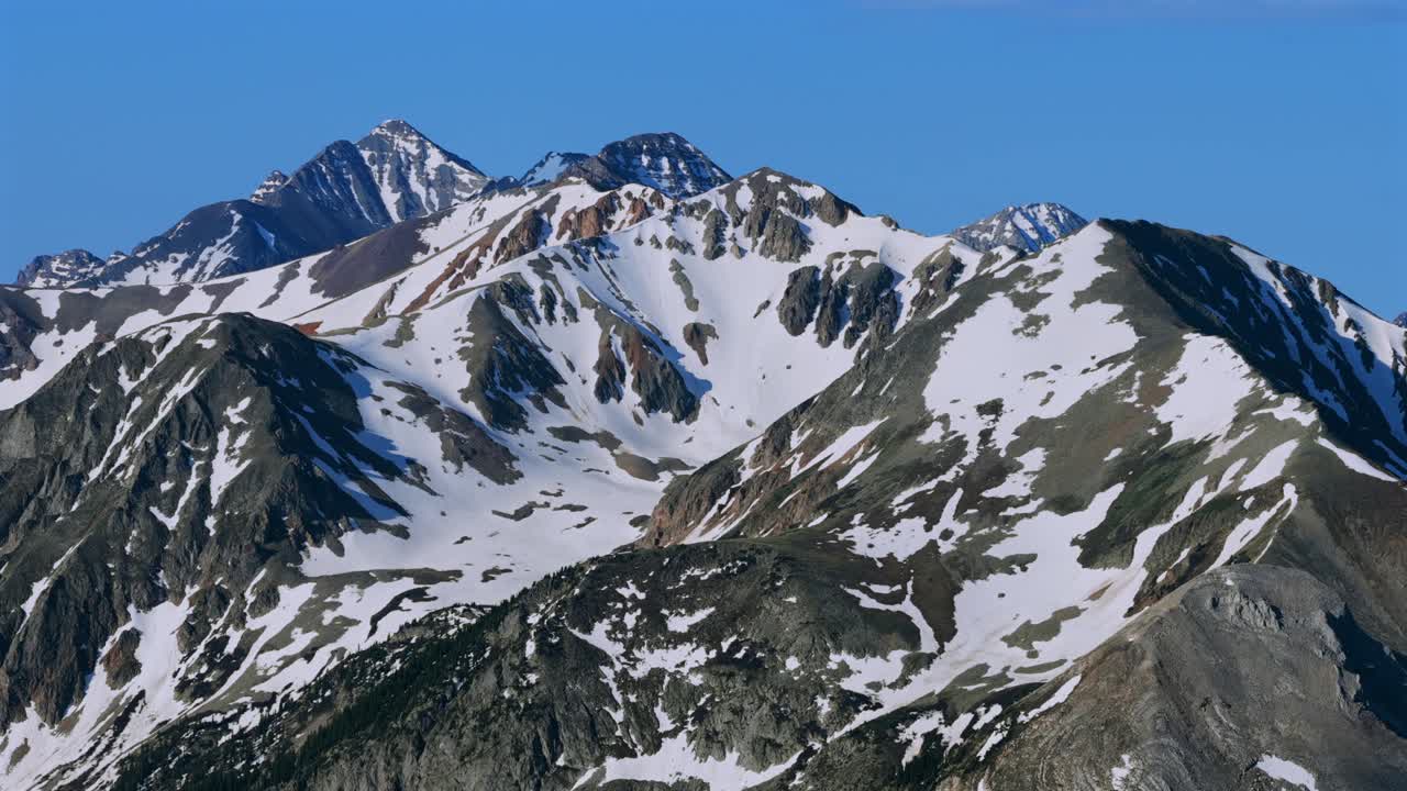 Springtime summer melting snow cover Conundrum Castle Peak Rocky Elk Mountains range Ashcroft AJAX Aspen Mountain aerial drone Castle Creek Maroon Bells Wilderness sunny blue sky parallax circle right
