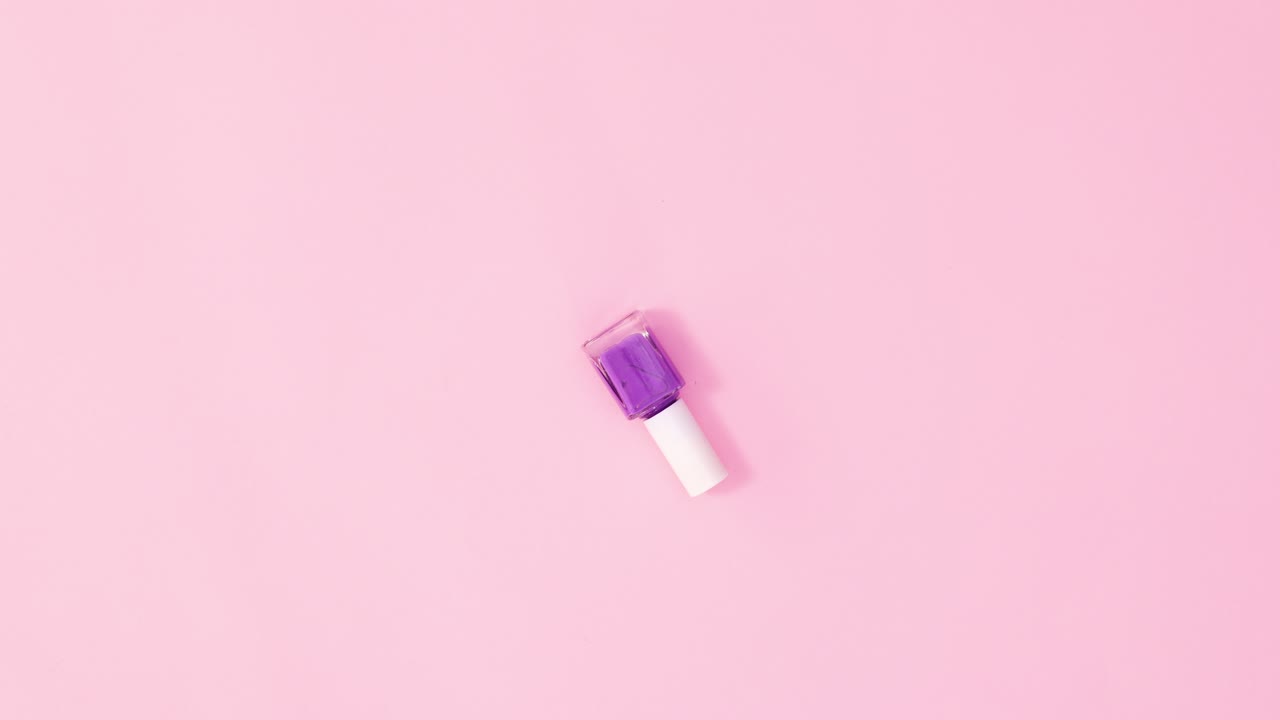 Manicure nail polish bottle rotating on pastel pink background. Stop motion flat lay