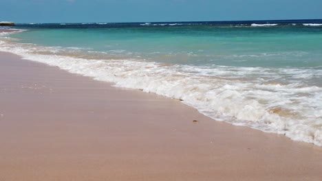 toma en cámara lenta de una orilla de mar turquesa andaman con olas que lamen la playa de arena dorada