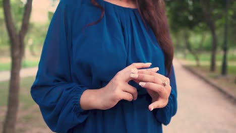 close up of woman wearing rings while standing outdoors in the park, camera is doing rotation around her