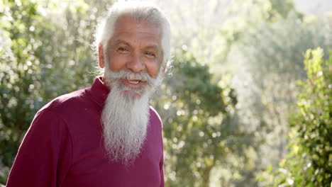 Retrato-De-Un-Hombre-Birracial-Mayor-Con-Barba-Blanca-Sonriendo-En-La-Naturaleza-Soleada,-Espacio-Para-Copiar,-Cámara-Lenta