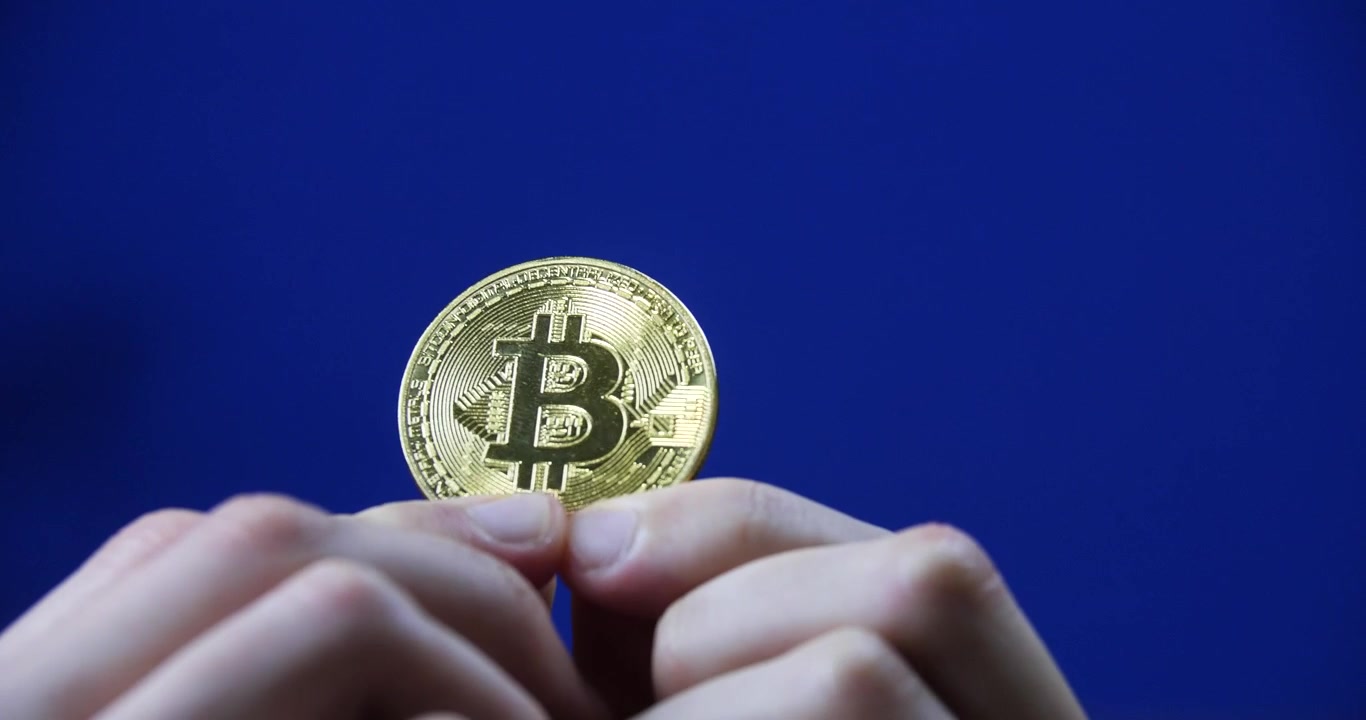 Mani che tengono una bellissima moneta Bitcoin su sfondo blu chroma key