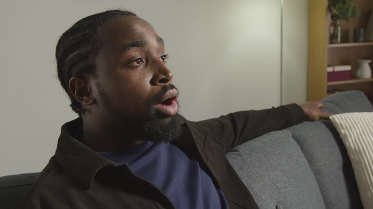 Angry Woman Standing Up Having Argument With Man Sitting On Sofa At Home