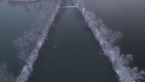 freezing bank or detroit river with small pond in between tree lines, aerial view