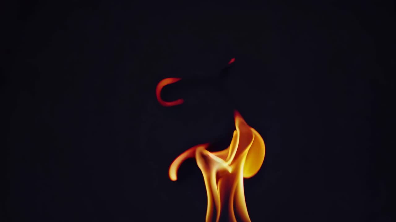 Abstract video of flames resembling a dancer and heart, captured from a low angle against a dark
