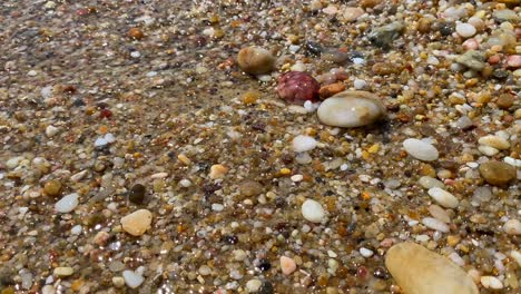 Wellen-Treffen-Auf-Wunderschöne,-Farbenfrohe-Natursteine,-Felsen,-Sand-Im-Meerwasser-Am-Strand-Von-Cavalière-Lavandou-Im-Süden-Frankreichs,-Natururlaub,-Statische-4K-Aufnahme