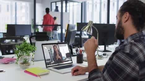middle eastern man talking on video call with female office colleague on laptop at office