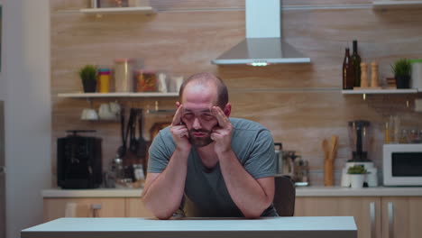 man with headaches sitting in the kitchen