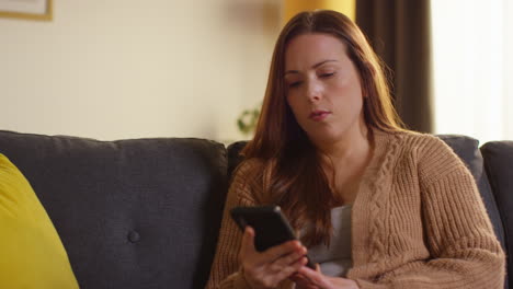 Mujer-Sentada-En-Un-Sofá-En-Casa-Viendo-Una-Película-O-Programa-O-Navegando-Por-Internet-En-Un-Teléfono-Móvil-9