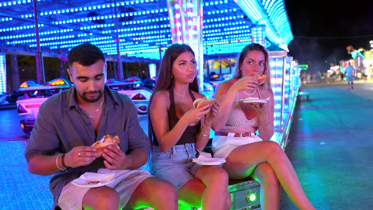 People Eating Hot Dogs at a Fairground