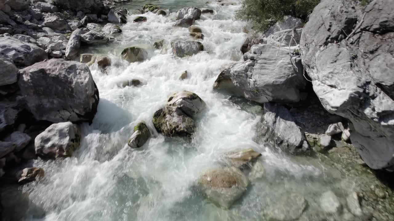 video de drone frontal avanzando sobre el rio valbone a vista de pájaro, video muy cerca del agua, 1 metro maximo, se ve el agua cristalina color turquesa rompiendo entre las rocas