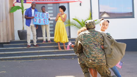 children hugging dad as multi-generation family welcoming army father home on leave with banner