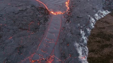 top down high angle drone aerial of molten lava fields and snow falling at the fagradalsfjall volcano eruption in iceland