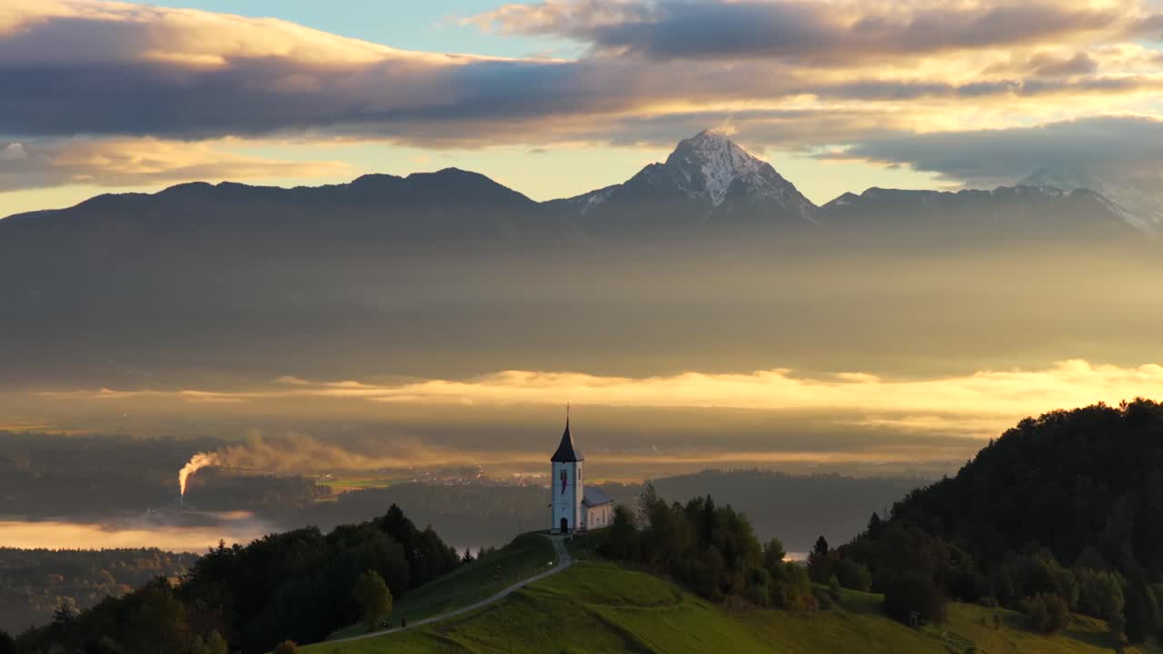 Aerial view of Slovenia's Jamnik church with Alps at sunrise