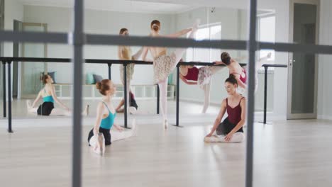 caucasian ballet female dancers stretching up with a barre before a ballet class