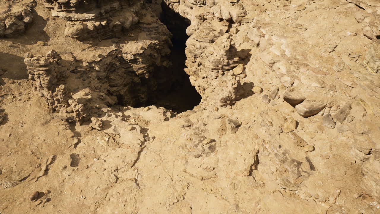 Rocky terrain reveals a deep crevice in the earth during a sunny day