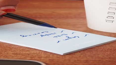 a close up of a hand writing a to-do list on a piece of paper