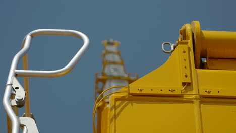 shallow focus looking up at yellow industrial crane boom arm under blue sky