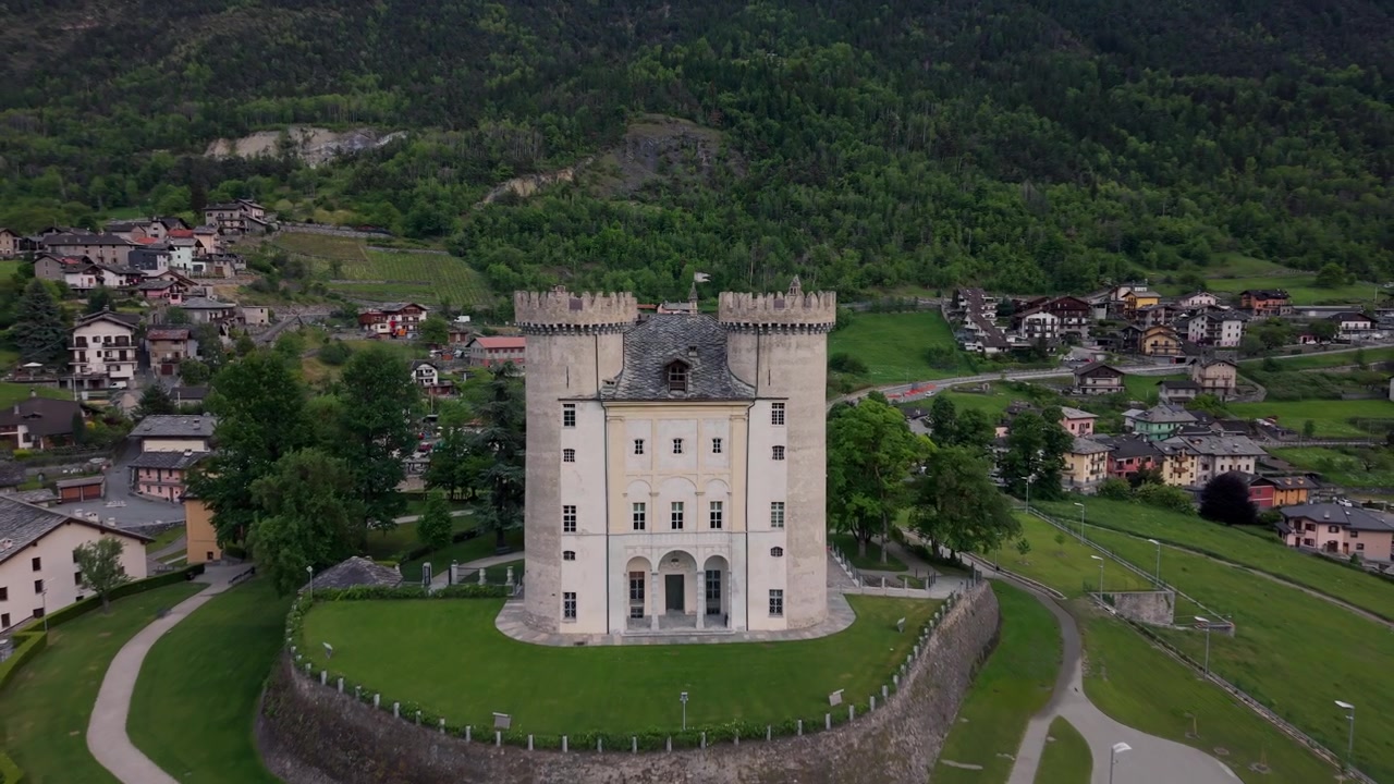 Hrad Aymavilles s výhledem na alpské město a údolí za soumraku v údolí Aosta, Itálie. Letecký záběr dozadu.