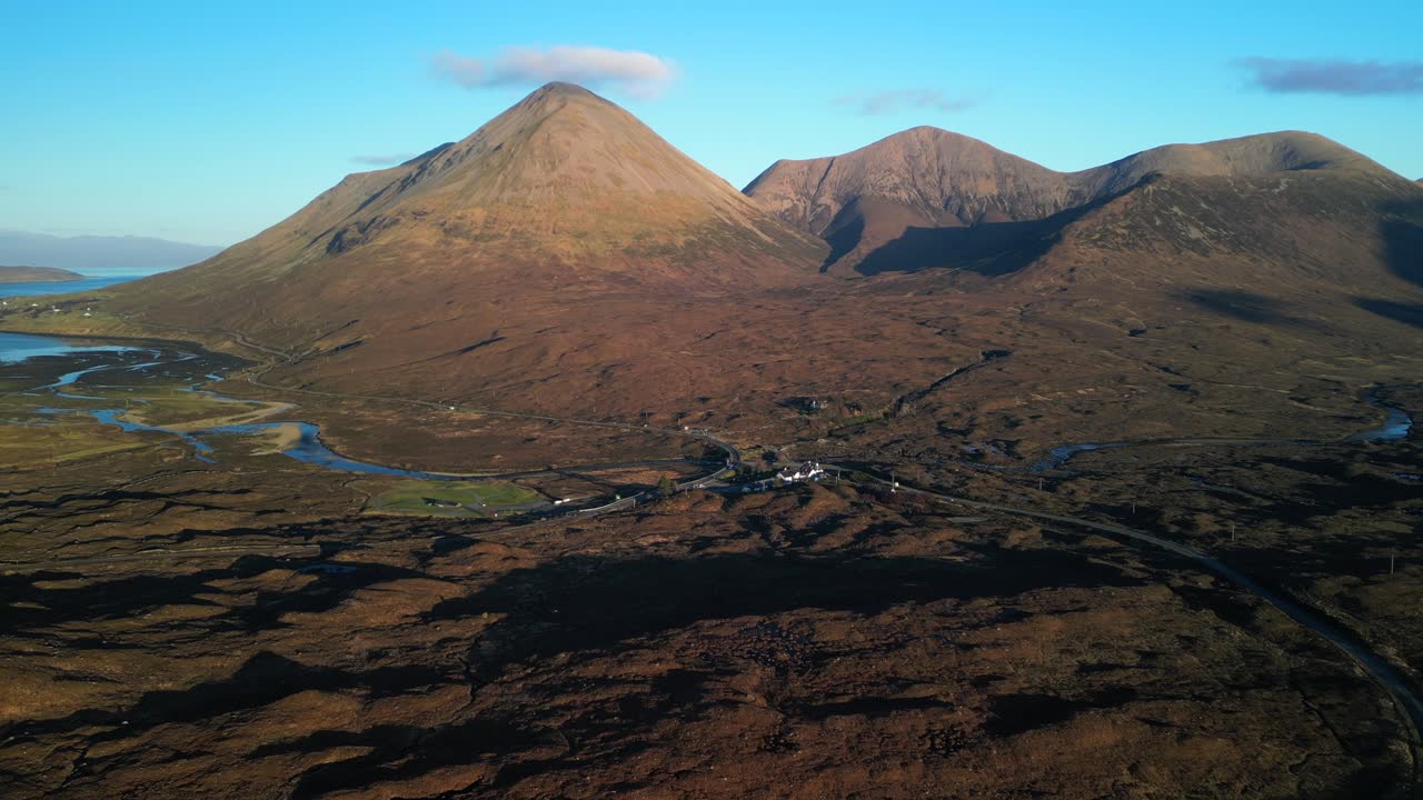 enfoque de alto nivel al hotel en sligachan con montañas cuillin rojas iluminadas por el sol al amanecer en la isla de skye, escocia