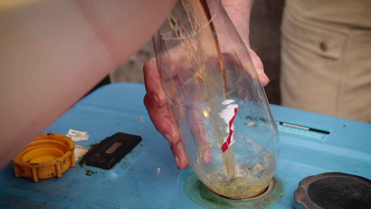 Image captures the action of pouring gasoline into a blue generator using a makeshift plastic bottle funnel
