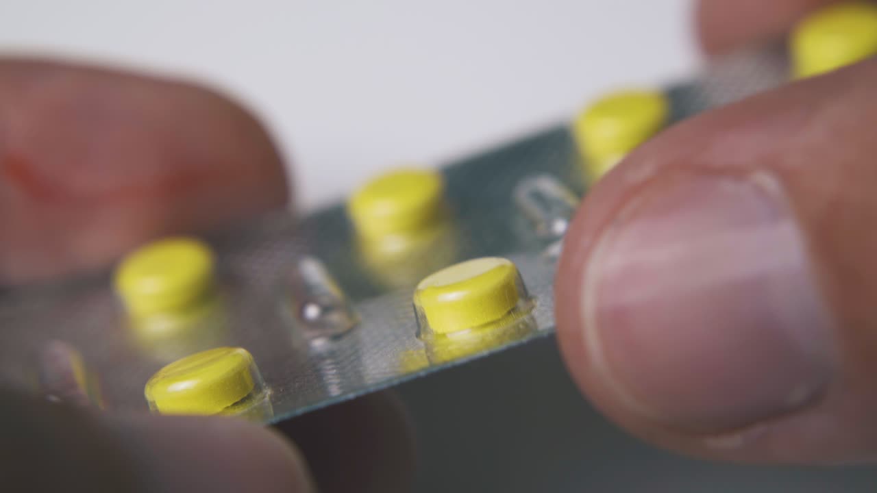 man holds blister with little tablets on white background