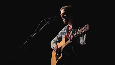 a musician is playing guitar on a large stage with audience members holding flashlights in the background. the auditorium is filled with beautiful flashing lights.