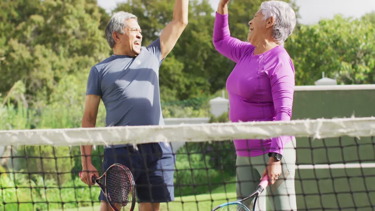 video de una feliz pareja de alto nivel biracial aplaudiendo durante el entrenamiento de tenis