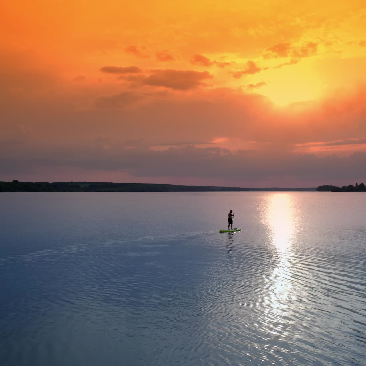 Silhouette di uomo in Stand Up Paddle Board. Giovane uomo che si allena su stand up paddle board al tramonto