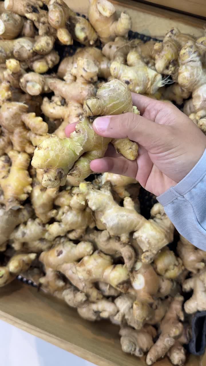 Mano che seleziona radici di zenzero fresche in un negozio di alimentari